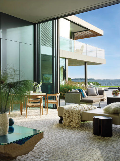 Spacious modern living room with panoramic water views, stylish furnishings, and natural textures.