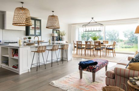 Spacious open-concept kitchen with large windows, woven pendant lamps, and a rustic wood dining table.