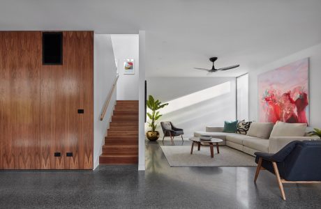 Modern interior with wood paneled walls, concrete floors, plush seating, and abstract artwork.