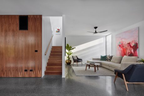 Modern interior with wood paneled walls, concrete floors, plush seating, and abstract artwork.