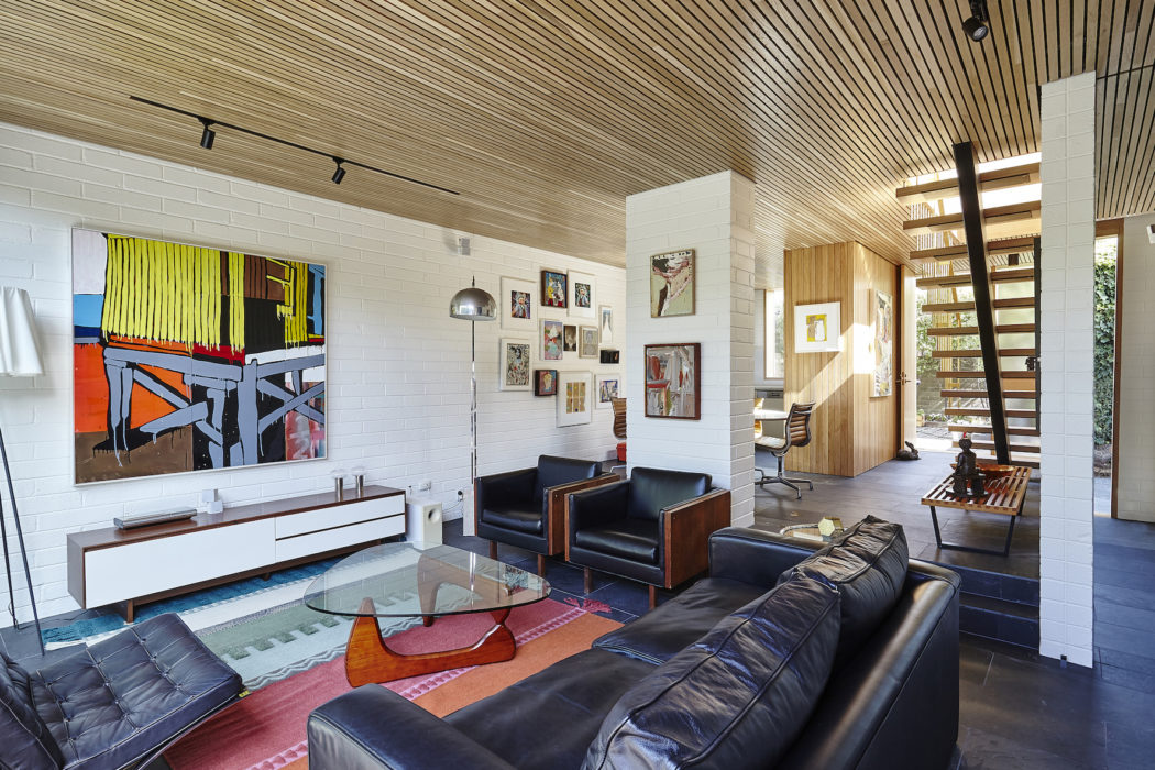 Vibrant modern living room with striking artwork, wooden ceiling, and leather furnishings.