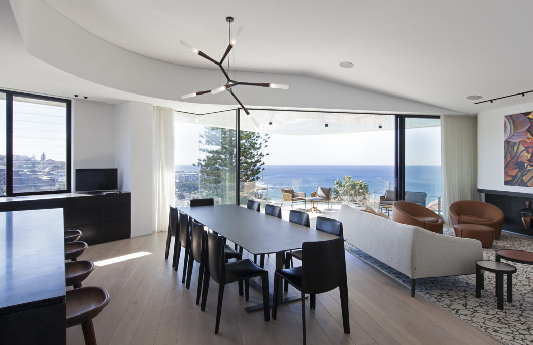 Sleek, modern dining room with a striking chandelier and panoramic ocean views.