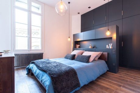 Elegant bedroom with high ceilings, pendant lights, and modern built-in shelving.
