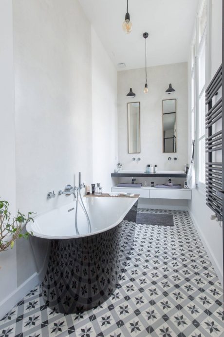 Bright, modern bathroom with patterned tile floor, white bathtub, and pendant lights.