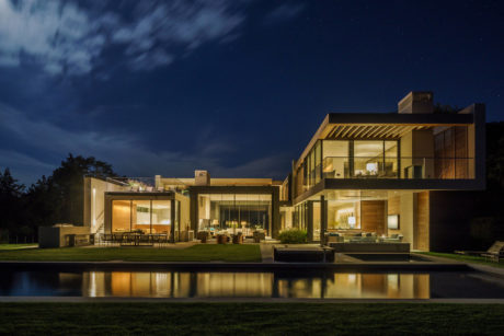 Expansive contemporary residence with glass walls, terraces, and reflective pool.