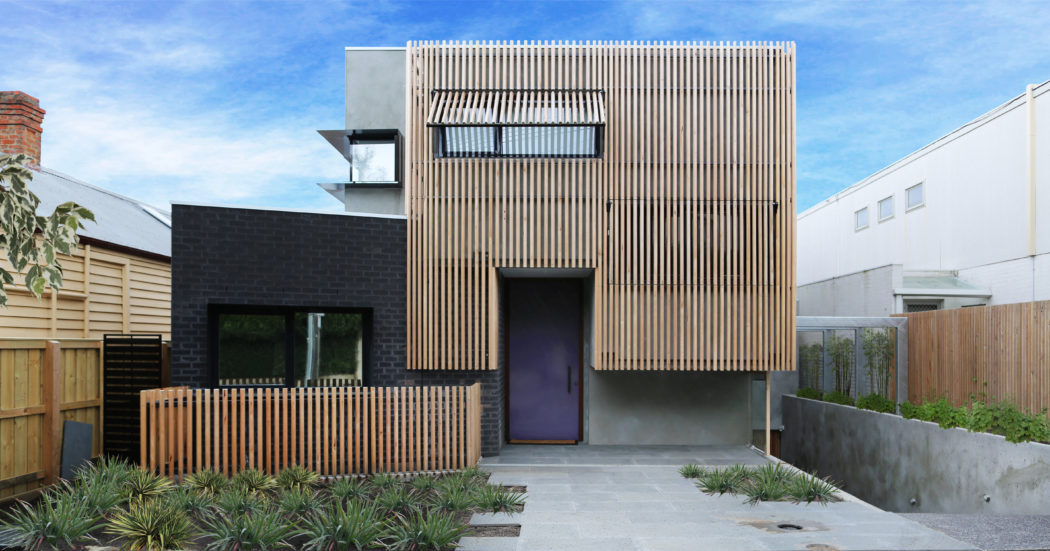Modern exterior with a mix of wooden slats, black brick, and glass elements.