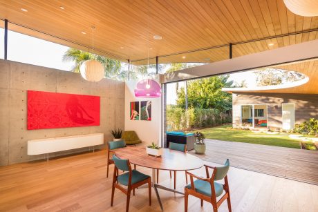 Vibrant modern interior with wood paneled ceiling, bold artwork, and expansive deck.