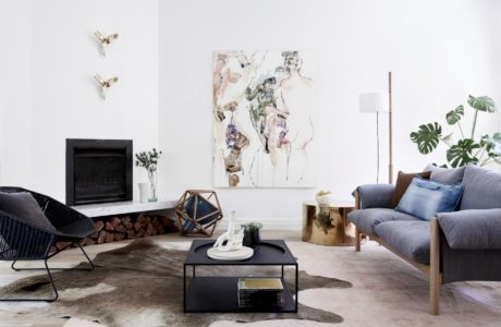 Minimalist living room with a fireplace, art piece, and tropical plant accents creating a cozy ambiance.