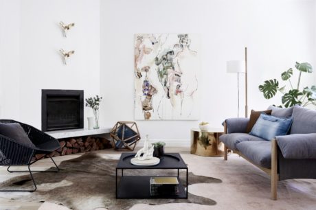 Minimalist living room with a fireplace, art piece, and tropical plant accents creating a cozy ambiance.