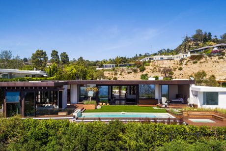 Stunning modern home nestled in lush greenery, featuring a sleek pool, deck, and panoramic views.