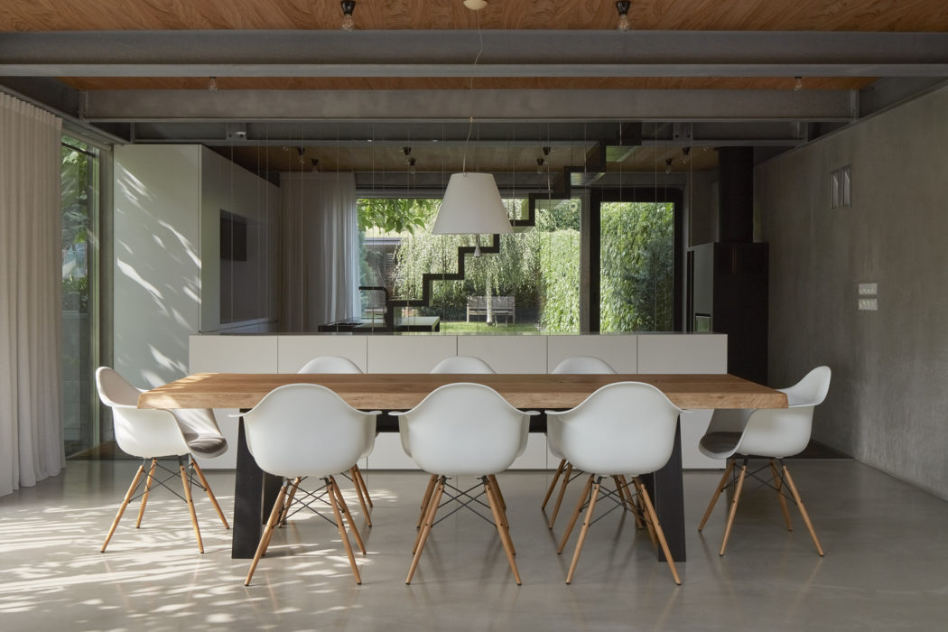 Sleek, modern dining room with wood accents, glass walls, and Eames-style chairs.