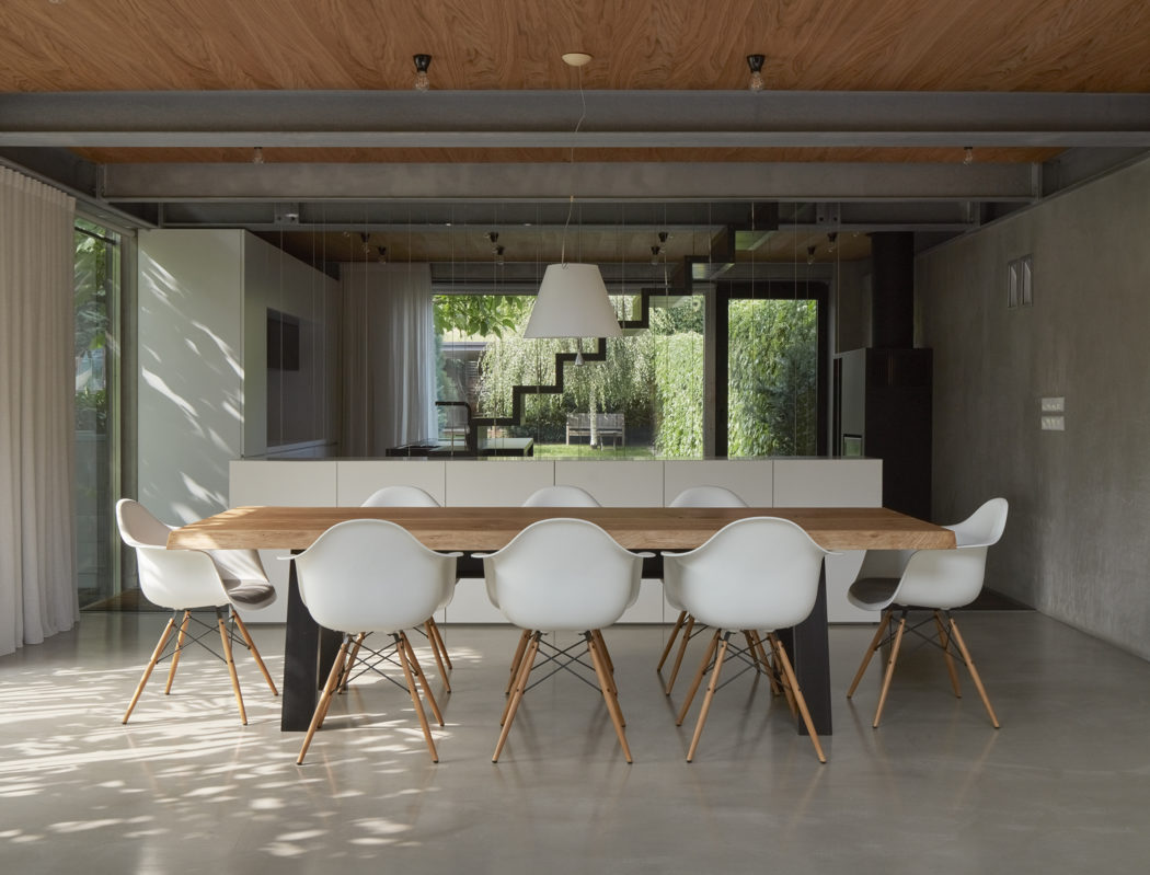 Sleek, modern dining room with wood accents, glass walls, and Eames-style chairs.