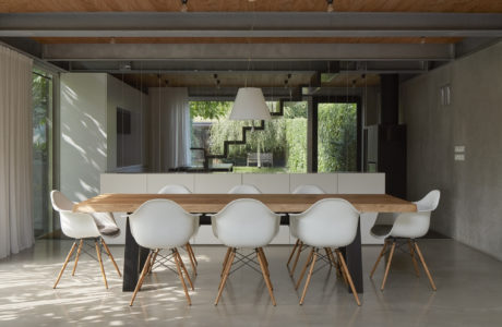 Sleek, modern dining room with wood accents, glass walls, and Eames-style chairs.