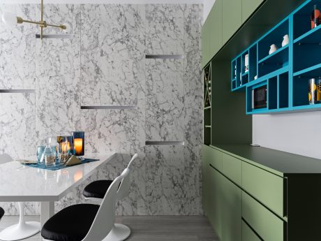 Sleek contemporary kitchen with marble backsplash, green cabinetry, and floating shelves.