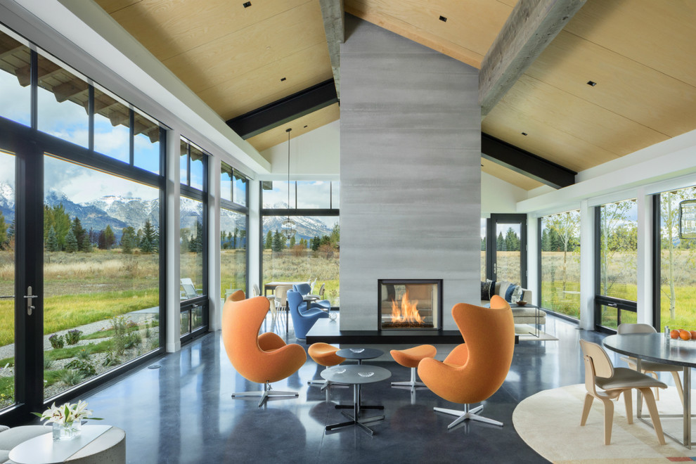 Expansive modern living space with floor-to-ceiling windows, central fireplace, and stylish furniture.
