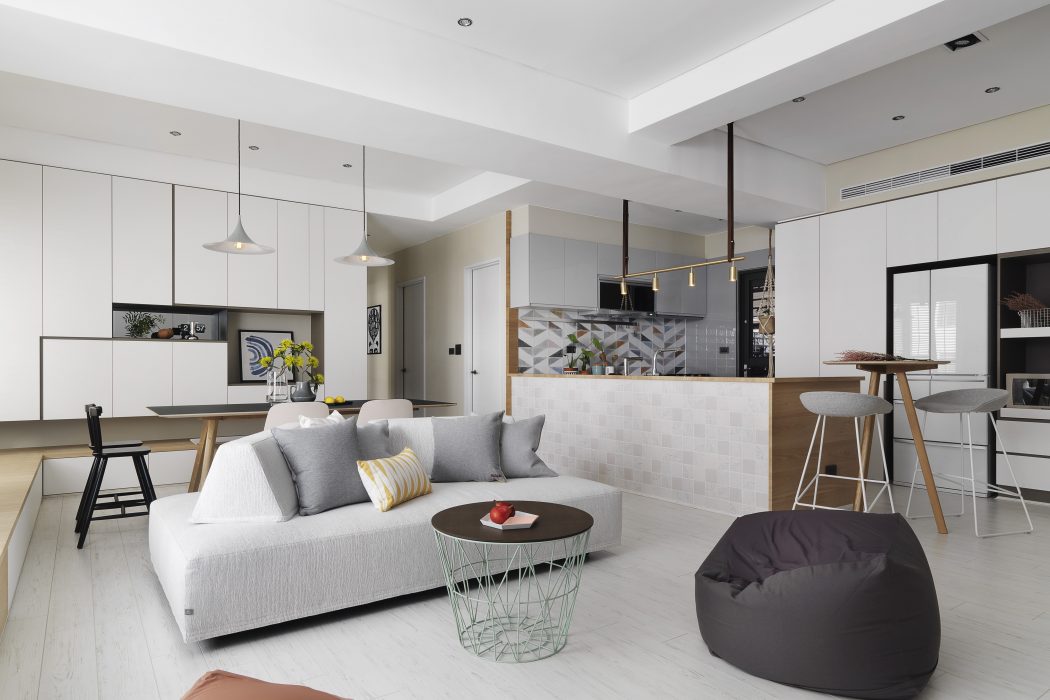 Sleek, modern interior with gray sofa, colorful accents, and geometric tile backsplash.