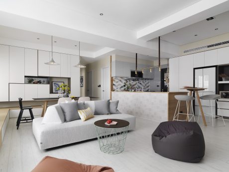 Sleek, modern interior with gray sofa, colorful accents, and geometric tile backsplash.