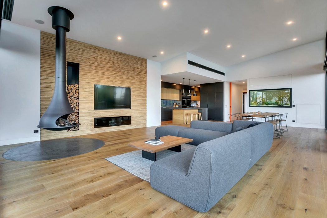 Spacious modern living room with sleek fireplace, hardwood floors, and open kitchen.