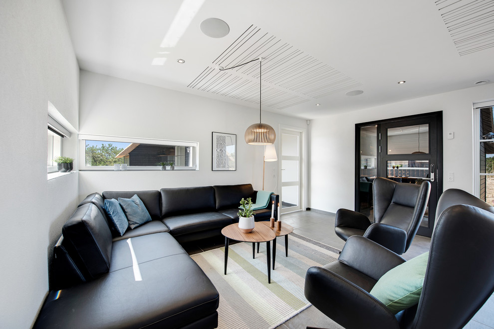 Bright, minimalist living room with black leather sofa, pendant light, and wooden coffee table.