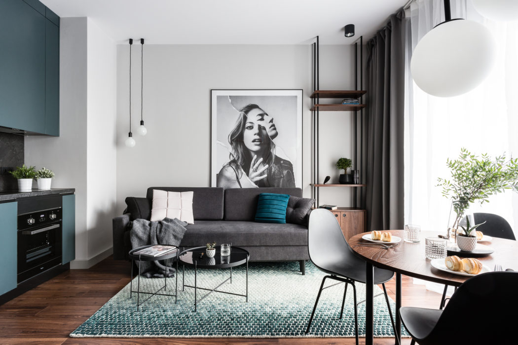 Sleek, modern living space with grey couch, artful wall decor, and wooden dining table.