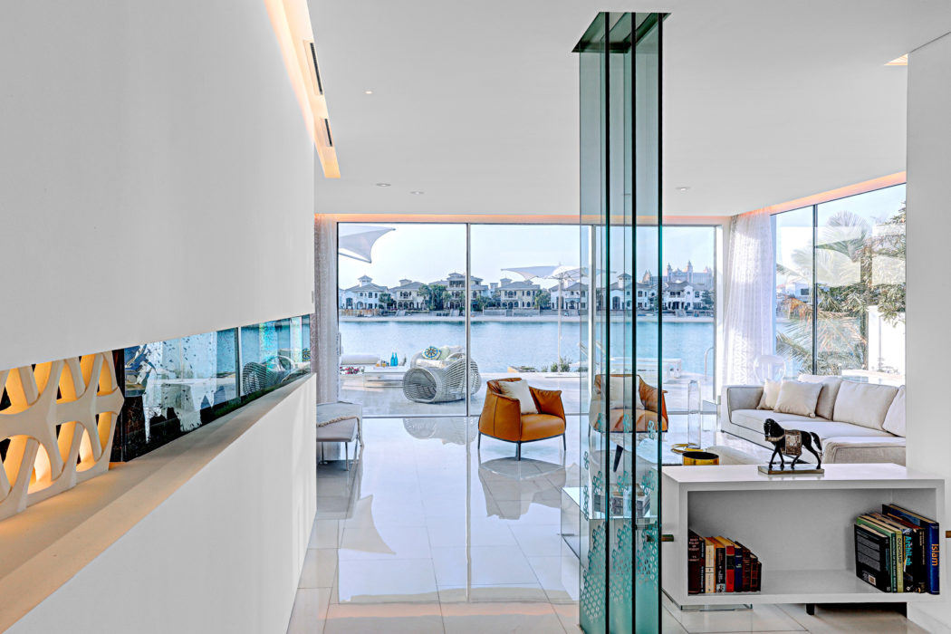 Sleek modern interior with expansive glass walls overlooking a lakeside view.