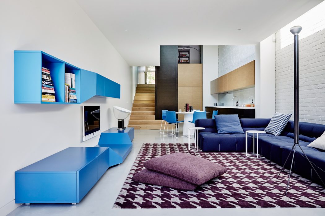 Bright, modern living space with bold blue cabinets, cozy sofa, and patterned rug.