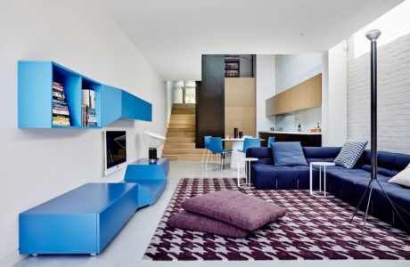 Bright, modern living space with bold blue cabinets, cozy sofa, and patterned rug.