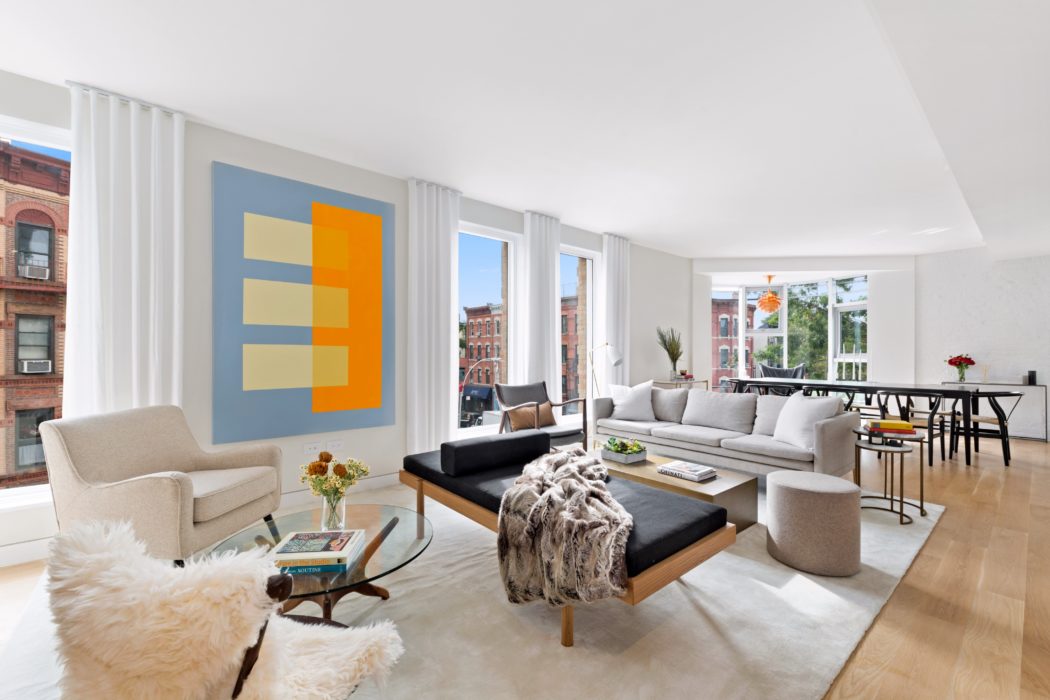 Spacious living room with large windows, modern furniture, and vibrant abstract artwork.