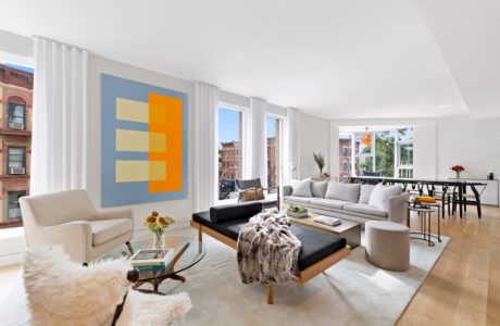 Spacious living room with large windows, modern furniture, and vibrant abstract artwork.