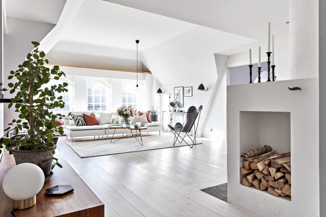 Bright, minimalist living room with architectural features, modern furnishings, and a cozy fireplace.