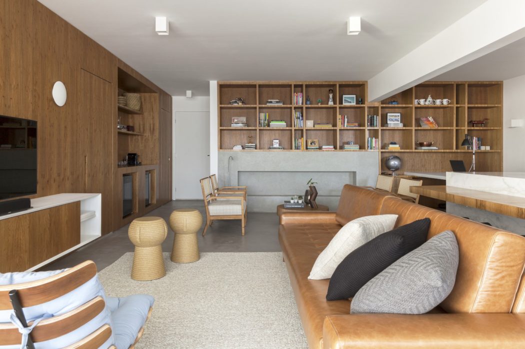 A modern, open-plan living space with built-in wooden shelving, leather sofas, and accent furnishings.