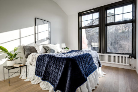 Cozy bedroom with large window, dark wood frames, and stylish quilt on the bed.