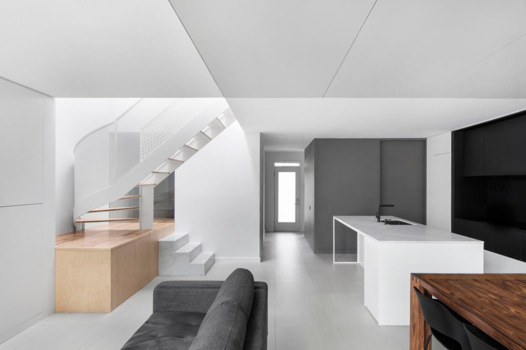 Minimalist interior with sleek staircase, modern kitchen, and monochrome color scheme.