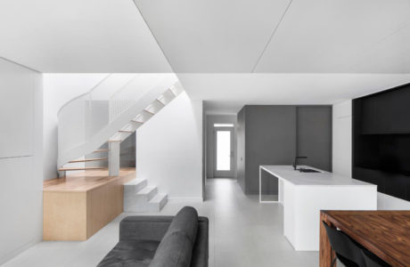 Minimalist interior with sleek staircase, modern kitchen, and monochrome color scheme.