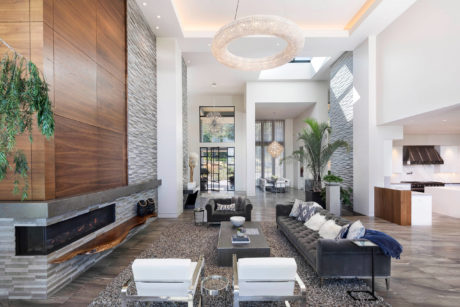 Sleek, modern living space with stone fireplace, crystal chandelier, and plush seating.