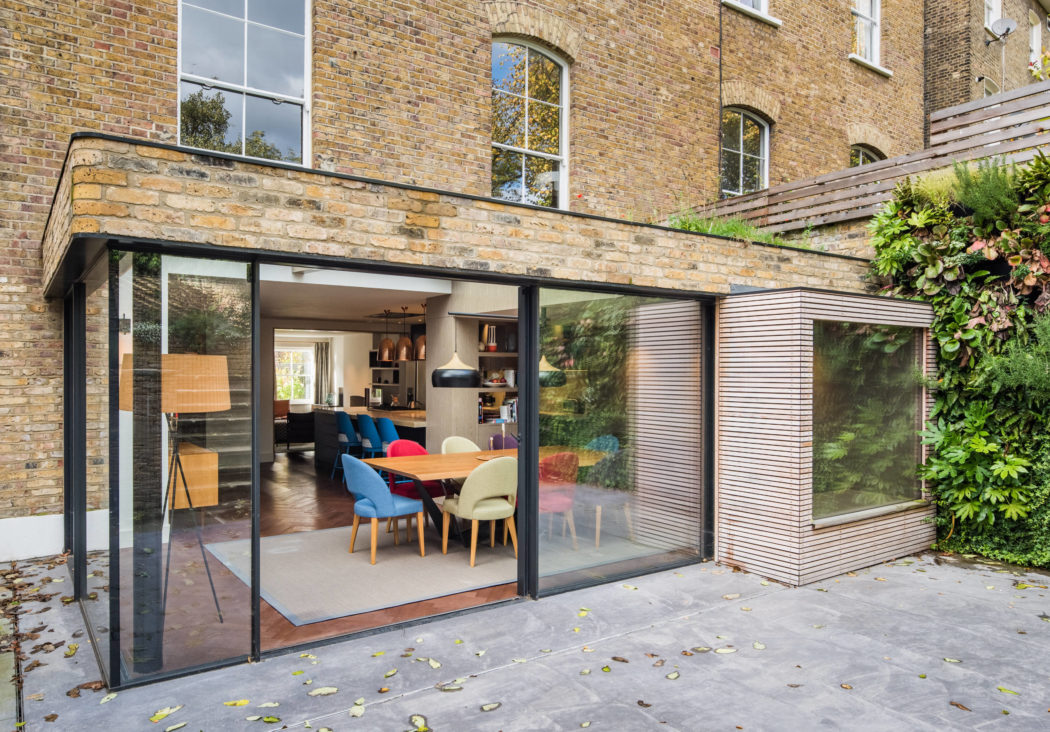Sleek glass-walled extension with open-plan dining area and contemporary furnishings.