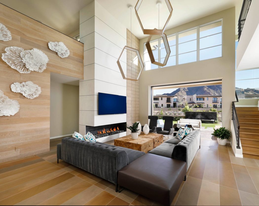 Spacious open-plan living room with wood paneling, geometric light fixtures, and mountain views.