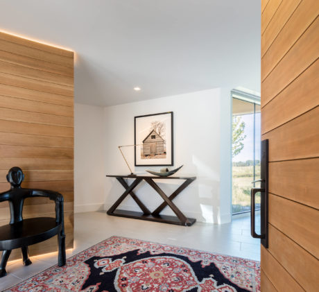 Elegant entryway with wooden paneling, modern console table, and ornate area rug.