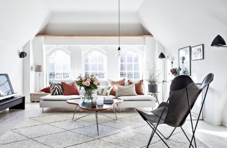 Bright, modern living room with arched windows, cozy sofa, and minimalist furnishings.