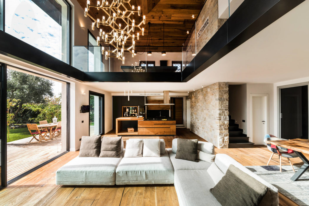 Spacious open-plan living area with high ceilings, wooden beams, and modern lighting.