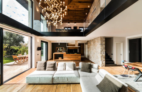 Spacious open-plan living area with high ceilings, wooden beams, and modern lighting.