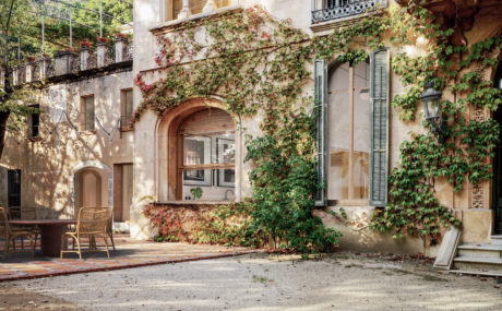 Charming Mediterranean-style facade with lush ivy-covered archways and rustic furnishings.