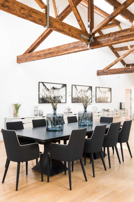 Rustic wooden beams frame a modern dining space with sleek black furniture and decor.