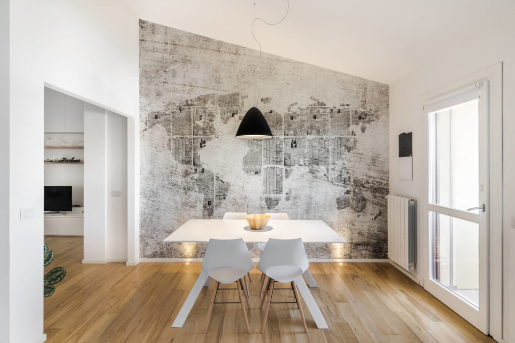 Minimalist dining space with sleek white table, modern chairs, and abstract wall mural.