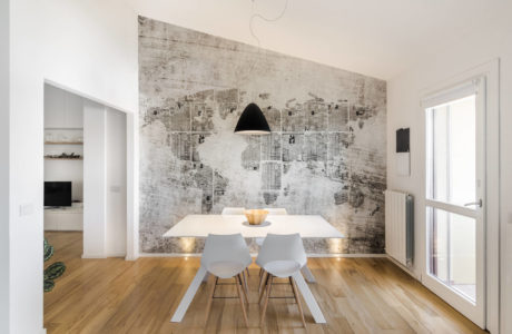 Minimalist dining space with sleek white table, modern chairs, and abstract wall mural.