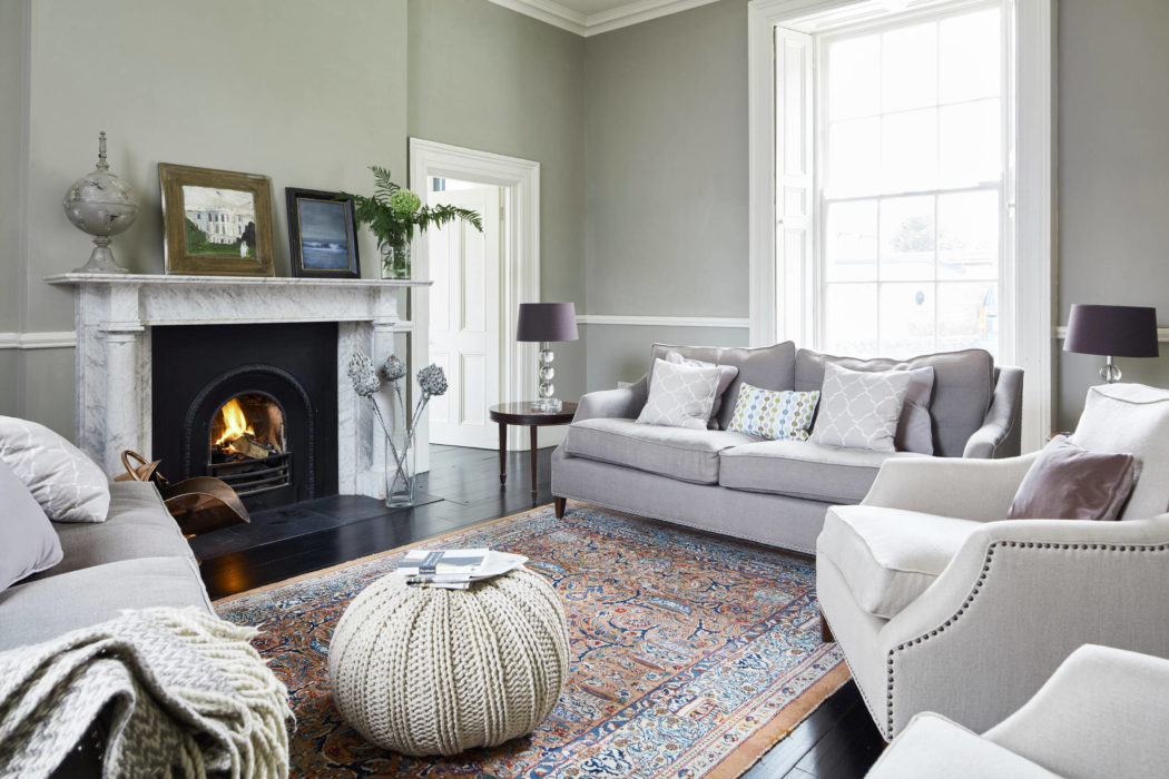 Cozy living room with fireplace, gray sofa, and ornate patterned rug.