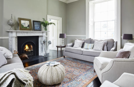 Cozy living room with fireplace, gray sofa, and ornate patterned rug.