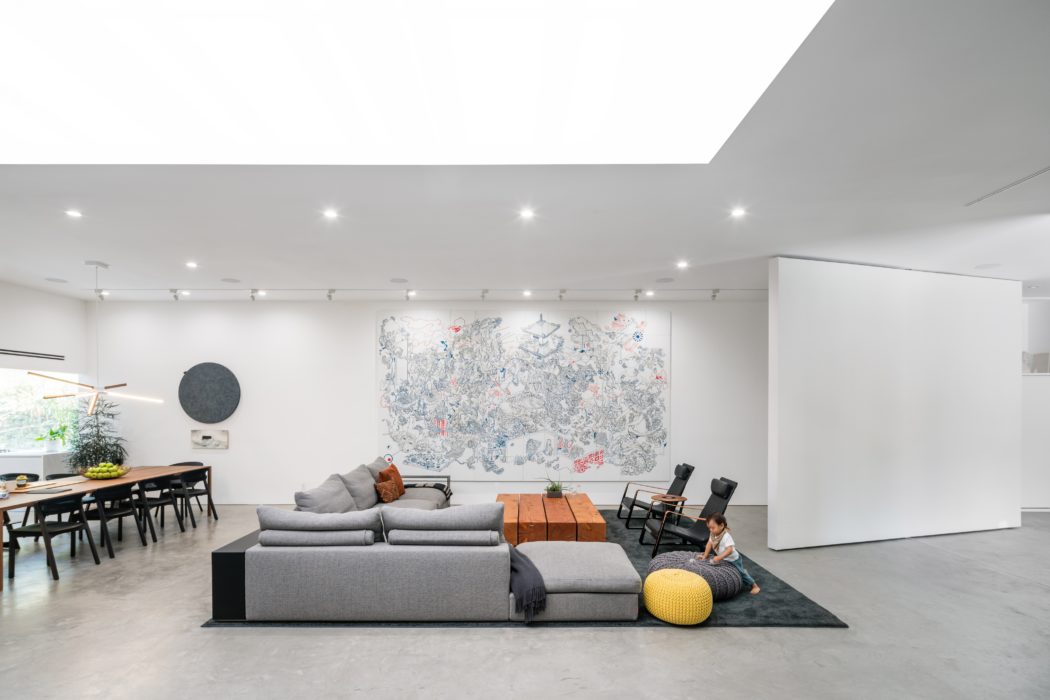 Modern, open-plan living space with minimalist furniture, large abstract artwork, and recessed lighting.