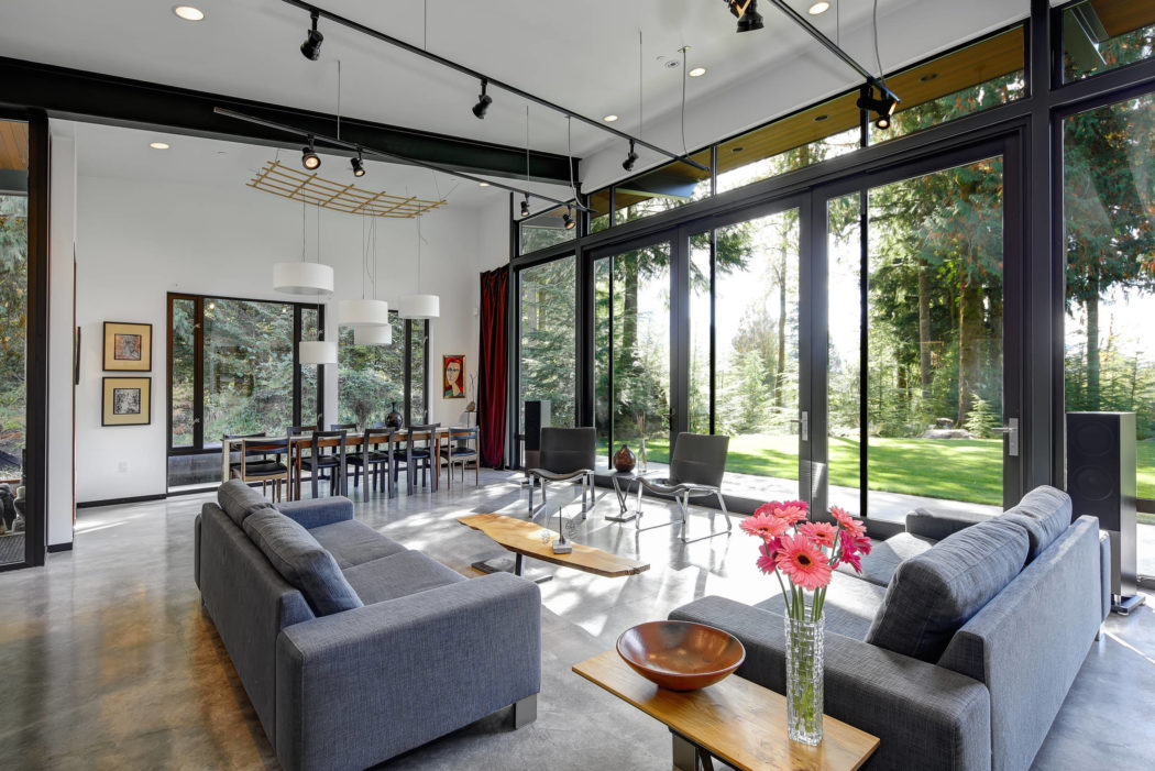 Spacious modern interior with floor-to-ceiling windows, track lighting, and wood accents.
