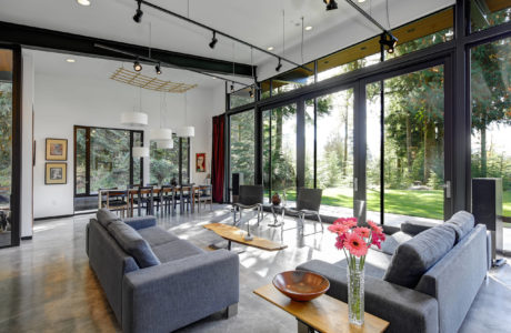 Spacious modern interior with floor-to-ceiling windows, track lighting, and wood accents.